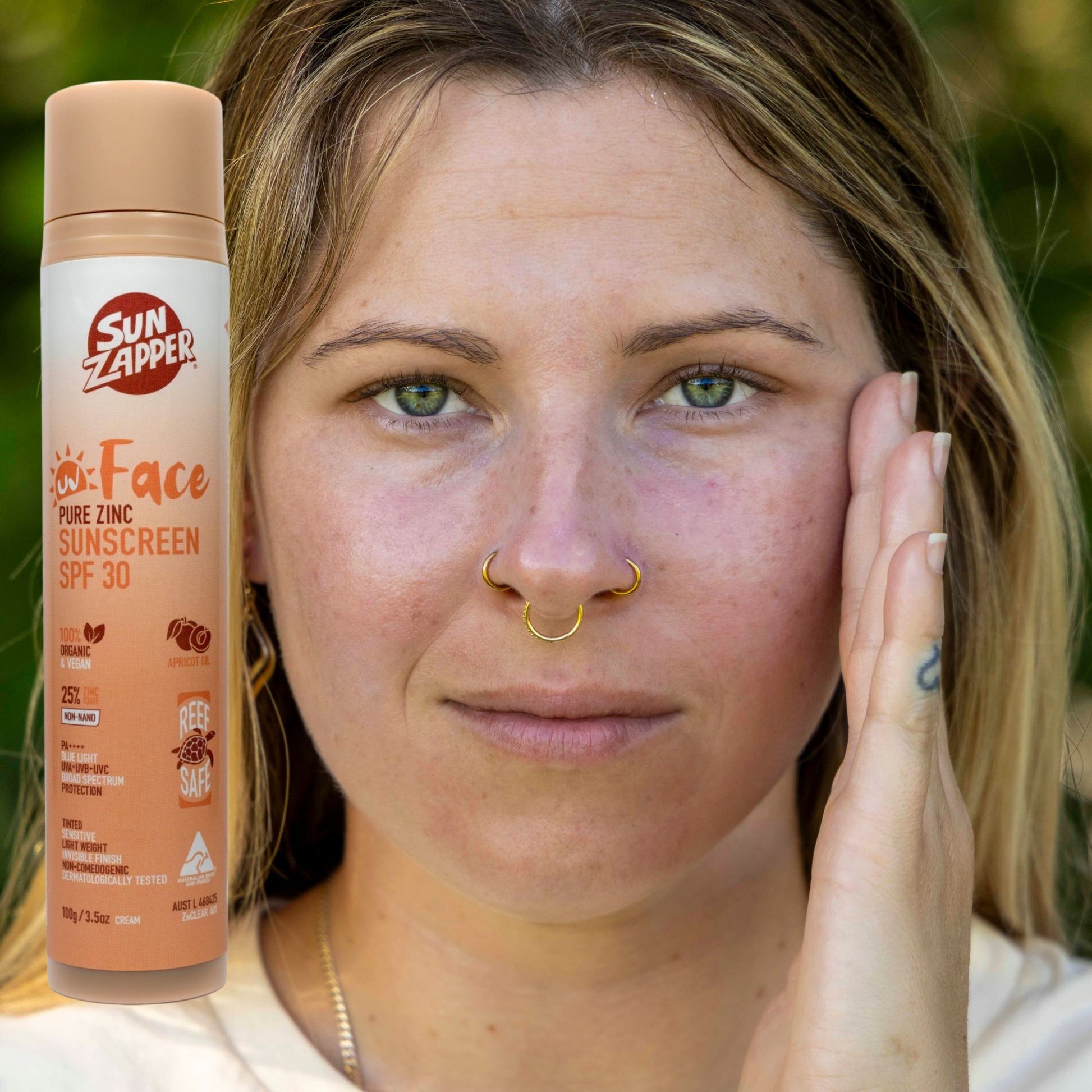 Woman with Sun Zapper face sunscreen bottle next to her face